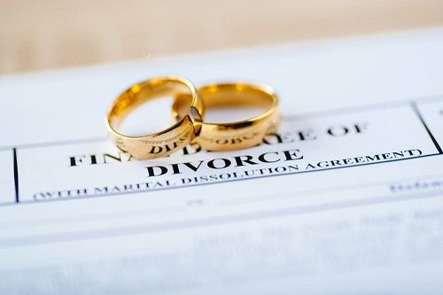 two wedding rings on top of a decree of divorce